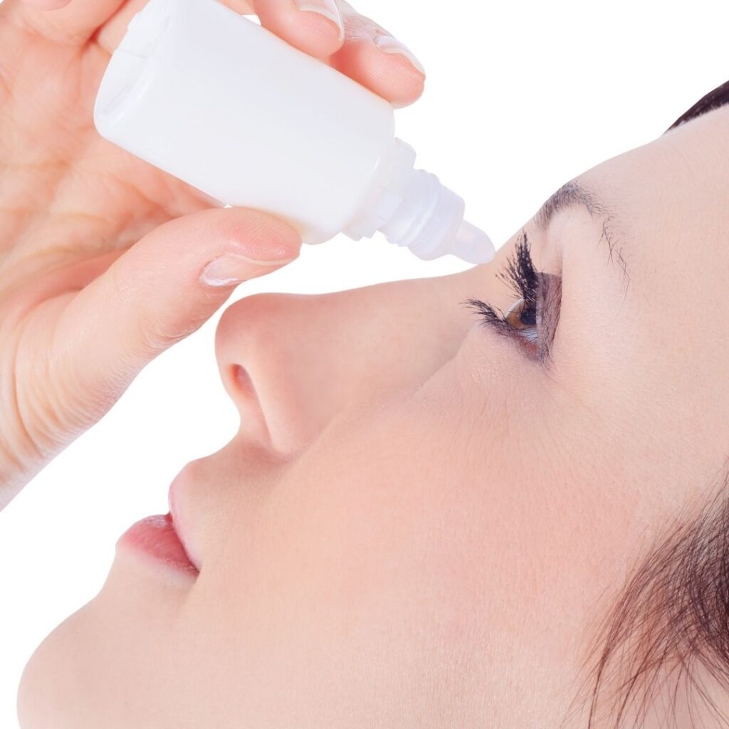 A woman putting eye drops in her eyes